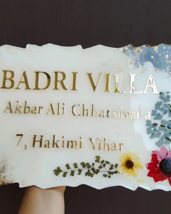 A custom resin house nameplate I created for 'Badri Villa'. It features the family name and address in gold acrylic letters, with a border of preserved flowers and gold leaf.