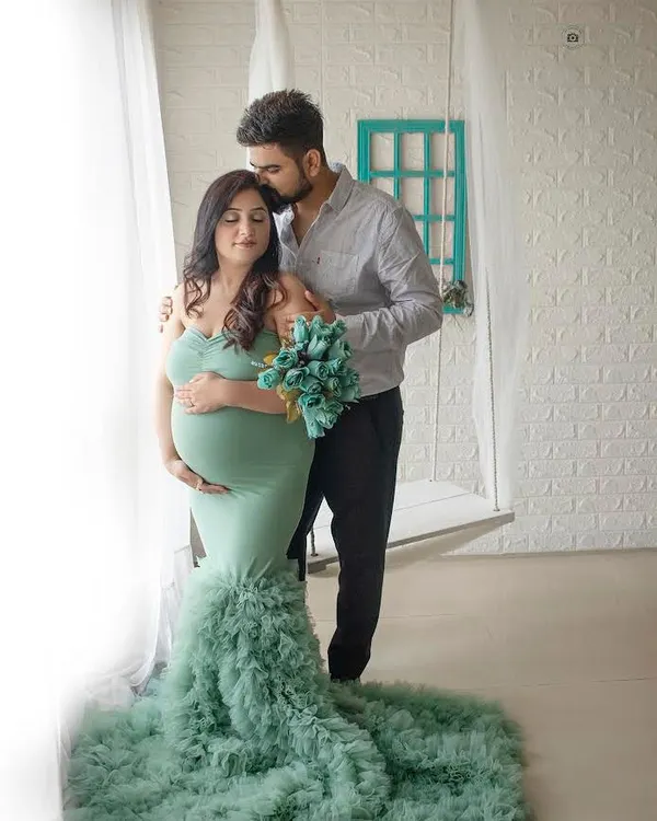 A tender moment captured by the window. The soft natural light and the flowing green gown make this maternity portrait feel so serene and beautiful.