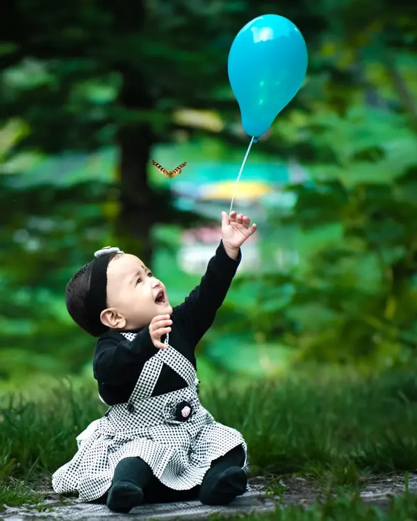 A moment of pure joy during a candid baby photoshoot. I love capturing these unscripted interactions, like this little one reaching for a balloon, with the soft, natural light creating a dreamy outdoor portrait.