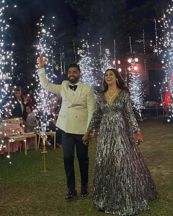 The couple makes a grand entrance at their bohemian-themed reception, walking through a tunnel of sparklers. The bride's shimmering gown and the groom's classic tuxedo look perfect against the magical backdrop.