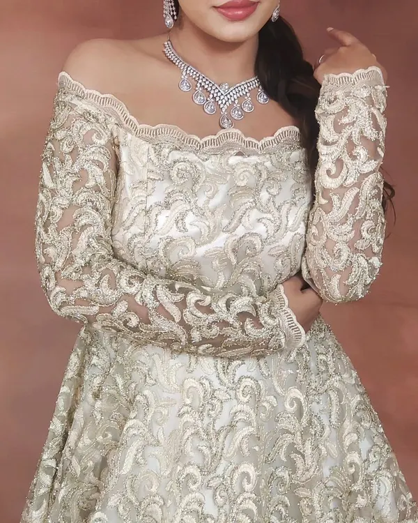 This elegant off-shoulder gown with intricate lacework is perfect for a sophisticated reception or cocktail party look. It pairs beautifully with a simple diamond necklace.