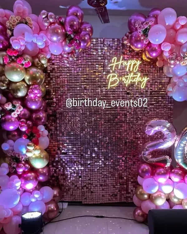 A full view of our stunning rose gold sequin wall, framed by an elaborate balloon garland in shades of pink, purple, and gold. This setup for a 26th birthday is pure glamour.
