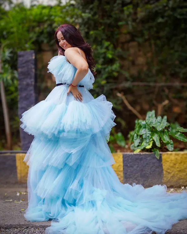 A full view of our dreamy light blue tiered ruffle gown. The layers of tulle create a cloud-like effect that moves beautifully, and the long train adds that extra touch of drama for an unforgettable outdoor maternity photo.