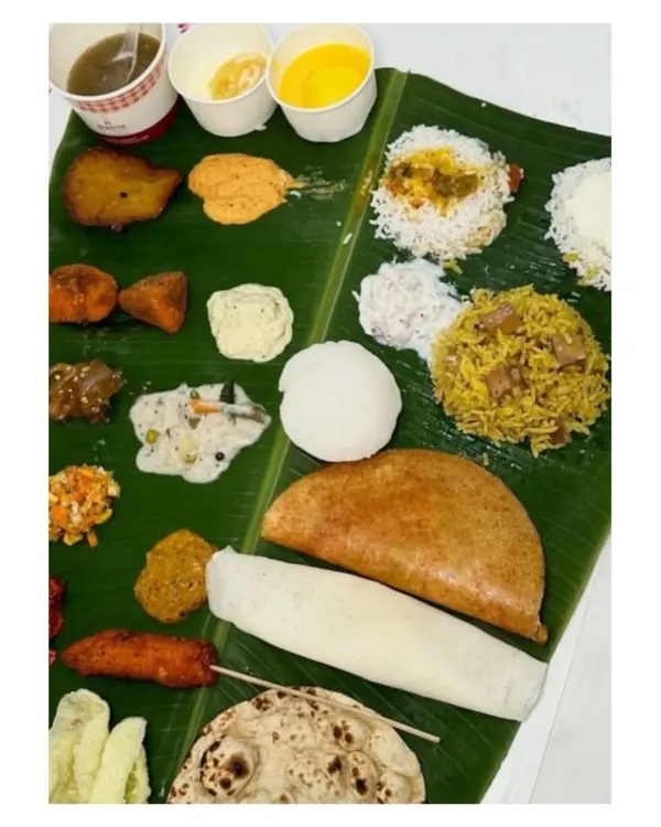 A complete South Indian vegetarian spread on a banana leaf. This meal features a variety of curries, rice dishes, dosa, vada, and sweets, offering a taste of everything.