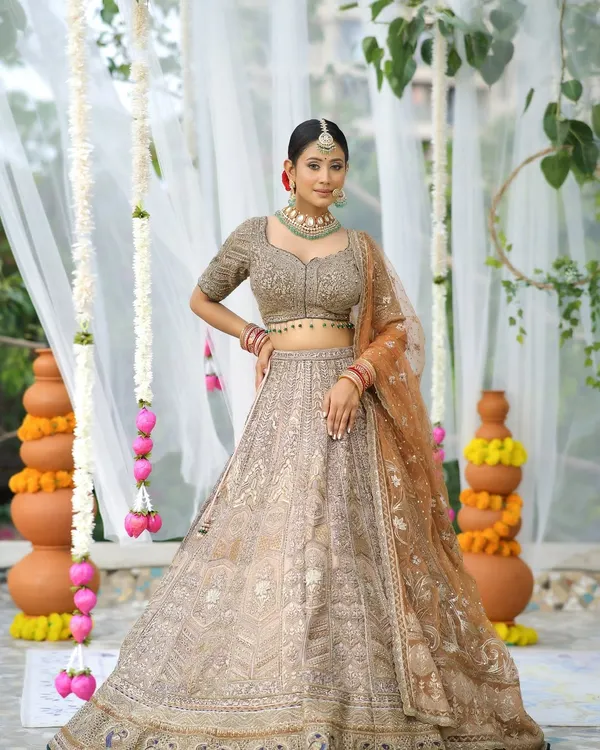 Timeless elegance that will keep winning hearts. This bride looks absolutely stunning in a beige and gold lehenga, with a soft-glam makeup look that enhances her natural beauty.