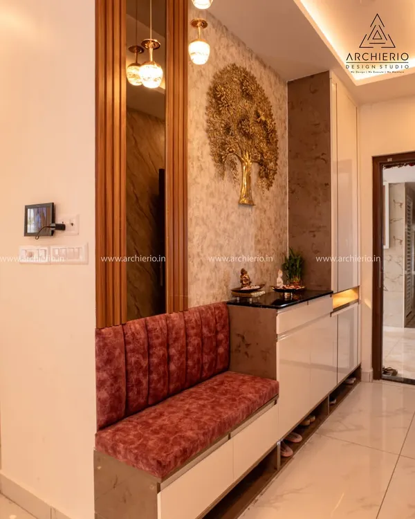 This luxurious foyer features a plush red velvet bench with integrated shoe storage, a gold tree-of-life mural, and elegant pendant lighting.