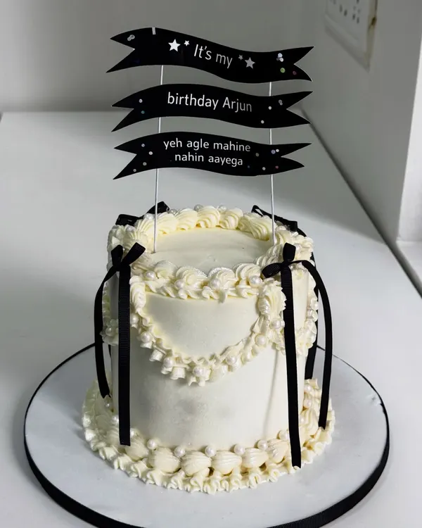 This cake understands the assignment. A Korean-style vintage design with clean piping, classic black and white drama, and a topper that adds a touch of relatable birthday humor.