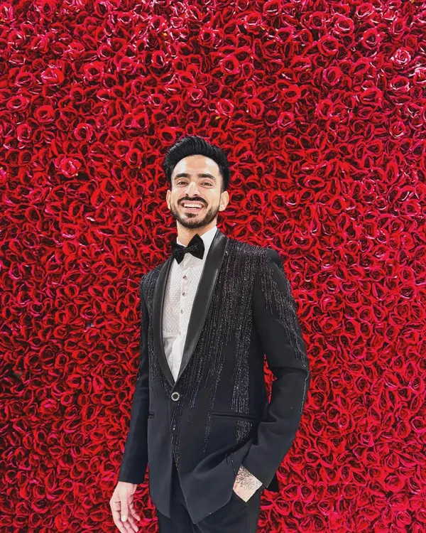 A client looking sharp against a wall of red roses in our Katdana-shower work tuxedo. The subtle sparkle on the jacket makes it a perfect choice for a glamorous evening reception.