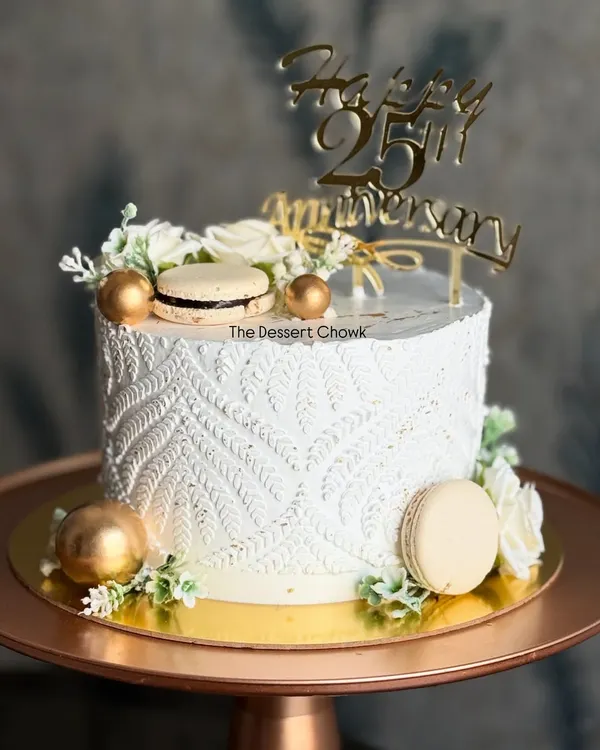 I love the texture on this tall anniversary cake, created using a stencil technique on fresh whipped cream. Paired with macarons and gold details, it creates a truly unique and elegant look.