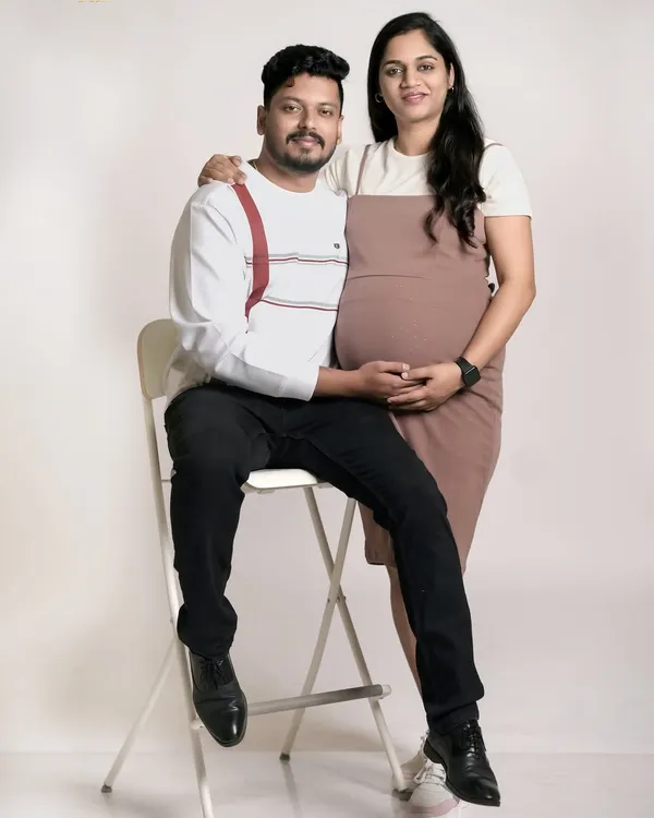 A simple and sweet studio portrait of an expecting couple. This classic pose beautifully highlights the baby bump and the supportive connection between the partners.