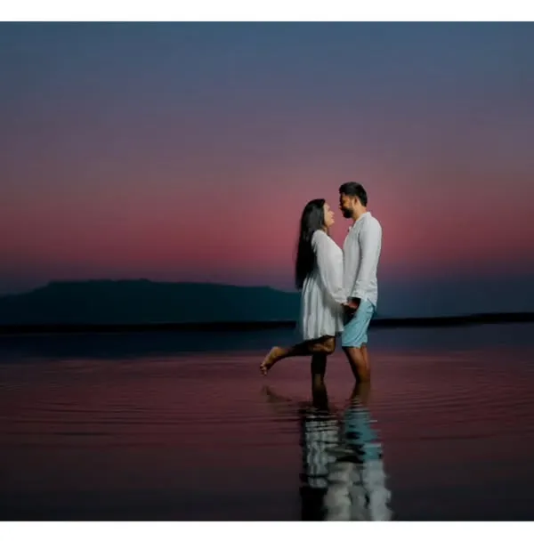 An intimate pre-wedding photo of a couple embracing in the water at dusk, with the deep colors of the sunset creating a romantic and serene atmosphere.