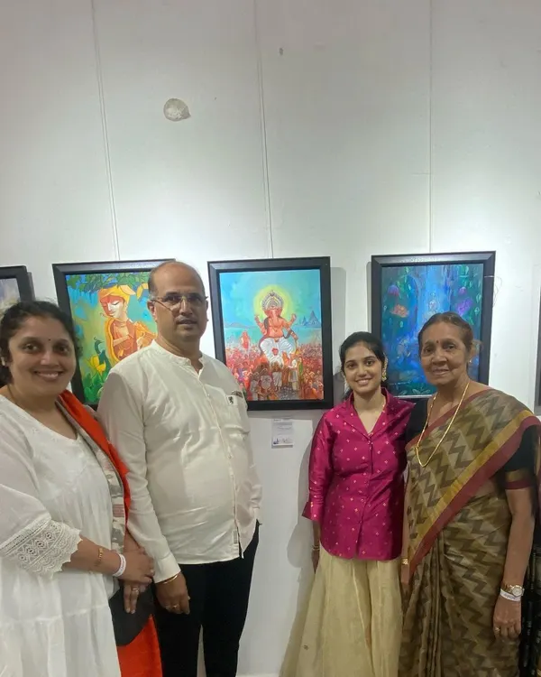 A student and her family posing proudly with her Ganesha painting at the CHITRAKAR art exhibition.