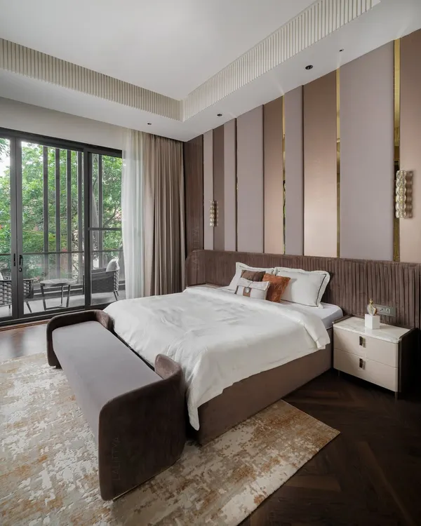This bedroom feels like a true retreat. We designed it with layered textures, warm tones, and sleek metallic accents on the feature wall. The bespoke furniture and soft daylight from the balcony create a setting that’s both inviting and refined.