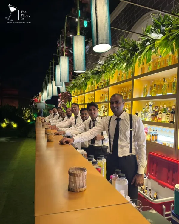 Our team of professional bartenders, lined up and ready for service at a large outdoor event. Dressed in sharp uniforms with suspenders, we are ready to bring both style and skill to your celebration.