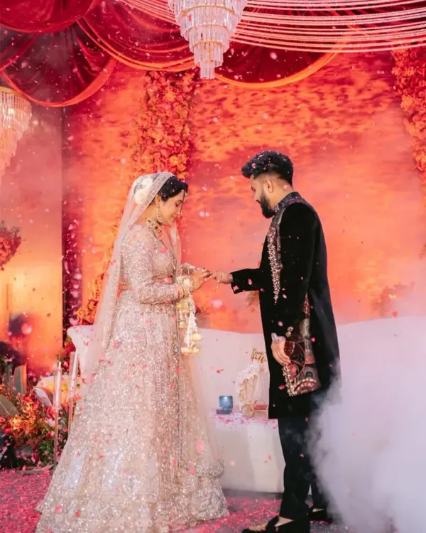 A moment of promise, captured in couture. The bride's heavily sequined lehenga and the groom's black velvet sherwani with detailed embroidery are designed to be a perfect pair for their engagement ceremony.