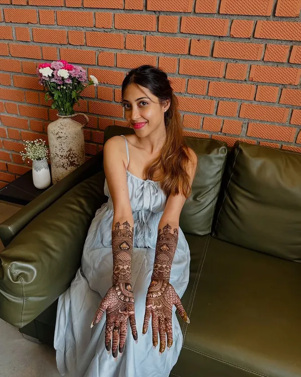 A happy bride proudly displaying her intricate full-arm mehndi. Her smile is the best reward for my detailed work.