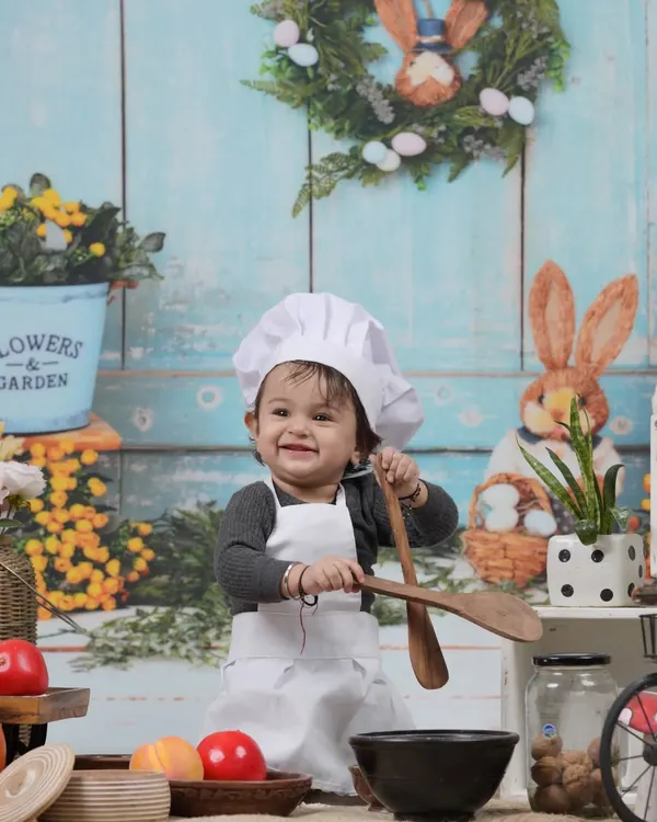 Our little chef, ready to cook up some fun. This adorable kitchen-themed studio setup is perfect for capturing your child's playful side.