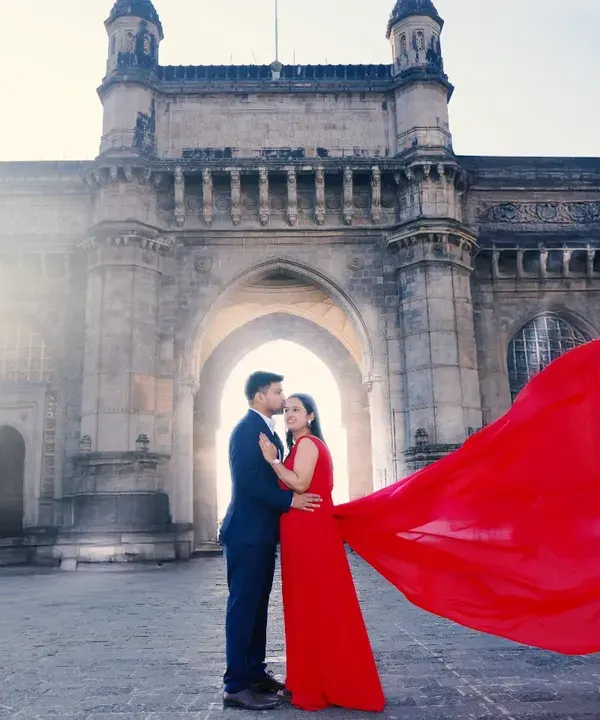 A breathtaking pre-wedding moment captured at Mumbai's iconic Gateway of India. We specialize in creating these dramatic, magazine-worthy shots, using creative elements like this flowing red gown to make your pre-wedding photography truly unforgettable.