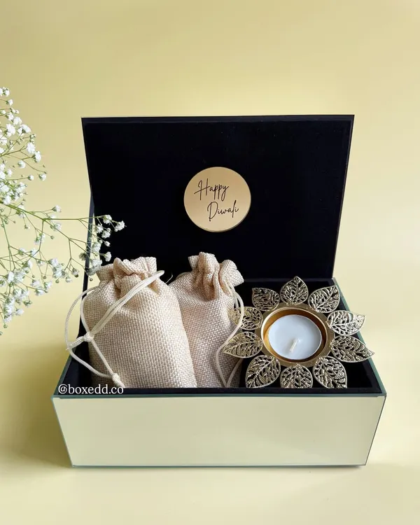 A classic Diwali gift box featuring a beautiful lotus diya and traditional potli bags, all housed in a luxurious glass and velvet hamper. It's a perfect blend of elegance and festive spirit for your corporate needs.