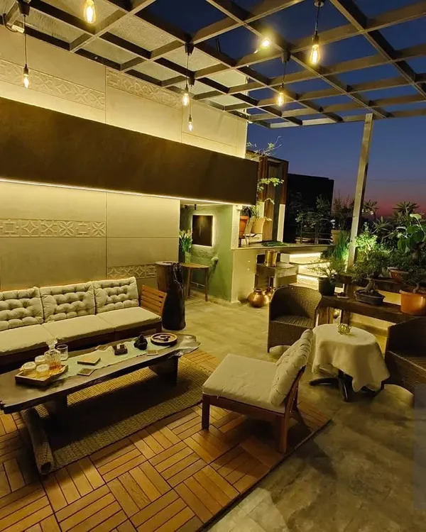 A terrace transformed into a stunning evening lounge. We used a wooden deck, comfortable low seating, and strings of Edison bulbs under a pergola to create a warm and inviting atmosphere perfect for private parties.