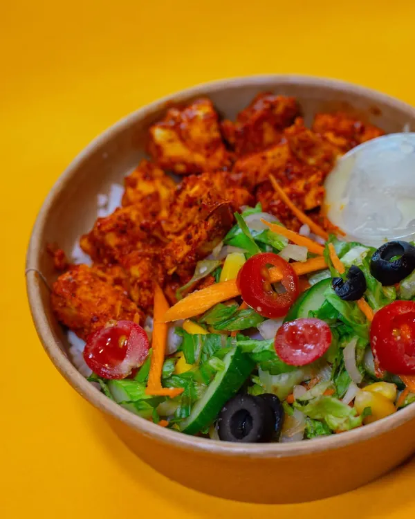 My Chicken Tikka Meal is a bestseller for a reason. It features tender, marinated chicken tikka pieces on a bed of rice, served with a fresh salad of tomatoes, cucumbers, and olives.