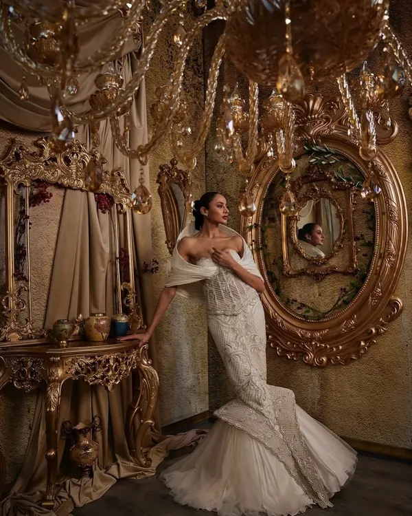 This ivory fit-and-flare gown is a study in contrasts. A meticulously hand-embellished, corseted bodice sculpts the form, while a dramatic structured hood adds a quiet power, creating an unforgettable bridal silhouette.