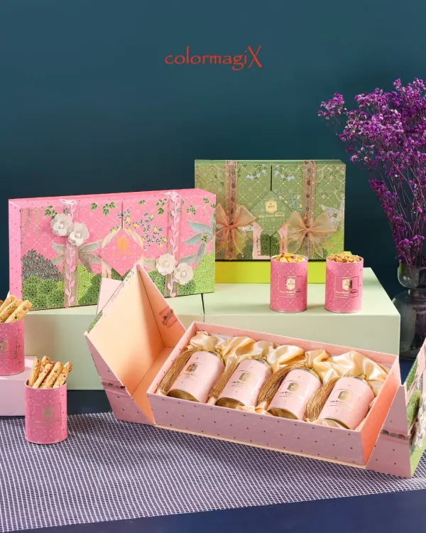 An elegant display of our luxury gift boxes in pink and green. This image highlights our intricate floral designs and the unique folding mechanism of the box, revealing a set of beautifully arranged smaller gift canisters inside.