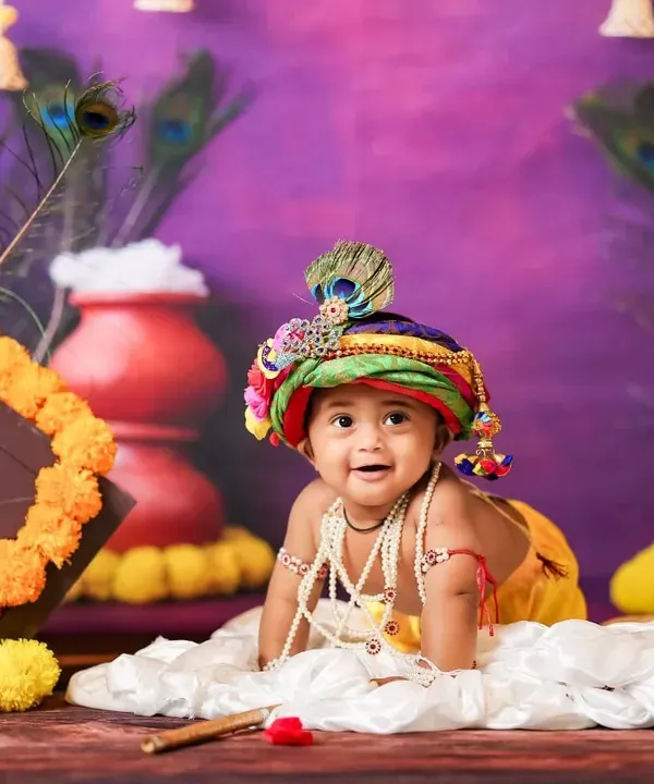 Our little Krishna crawling in a vibrant setup for Janmashtami, complete with marigolds, peacock feathers, and a pot of butter.