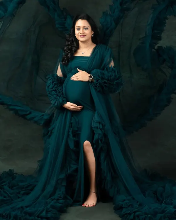 This is the moment to celebrate you. In my studio, I use dramatic lighting and beautiful gowns, like this flowing teal one, to capture the pure power and elegance of motherhood.
