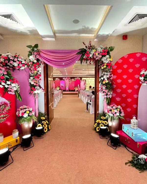 A full view of our flamingo-themed Haldi entrance. The pink and red floral arrangements, combined with whimsical flamingo panels and colorful trunks, create a fun, modern, and cohesive look that welcomes guests into a vibrant space.