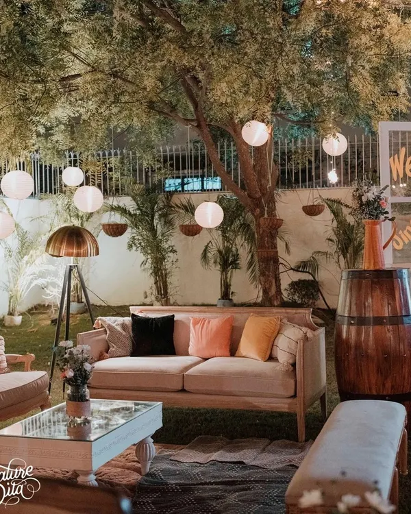 For this 50th anniversary, I created a cozy lounge area under the trees. The setup featured comfortable sofas with colorful cushions, a vintage floor lamp, and hanging paper lanterns for soft, ambient lighting.
