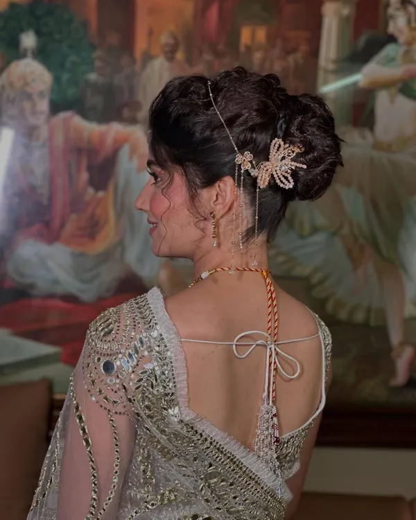 A side view of this romantic updo, showcasing the intricate weaving and the delicate, dangling hair accessory that adds a touch of magic. This is a perfect hairstyle for a sangeet or reception.