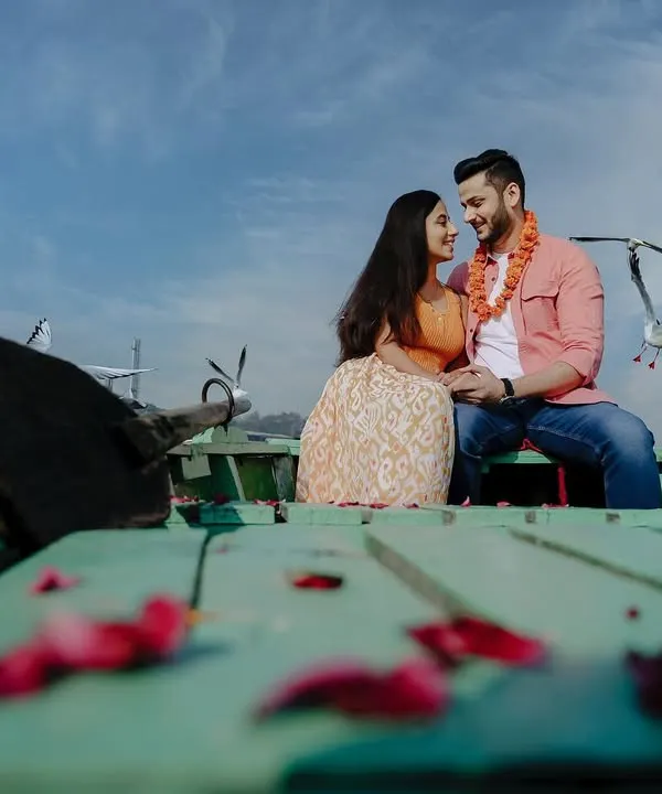 A classic Bollywood-style pre-wedding shot on a boat at Yamuna Ghat. The flock of birds, blue sky, and the couple's happy gaze create a picture-perfect romantic moment.