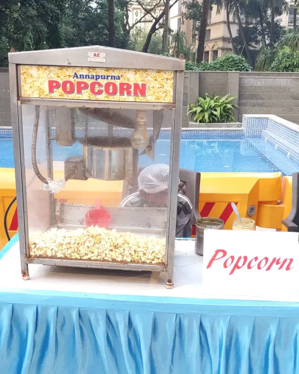 Our popcorn machine rental is perfect for any event, set up here by a pool. I provide the machine and an operator to ensure a constant supply of fresh popcorn for your guests.