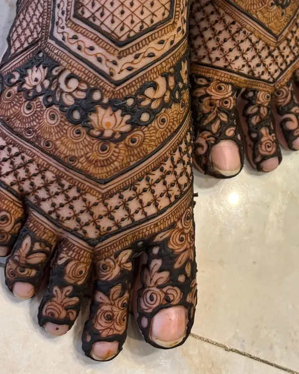 A close-up of the intricate details on this bridal feet mehendi. You can see the delicate lotus flowers and the fine lines of the checkerboard pattern on the toes.