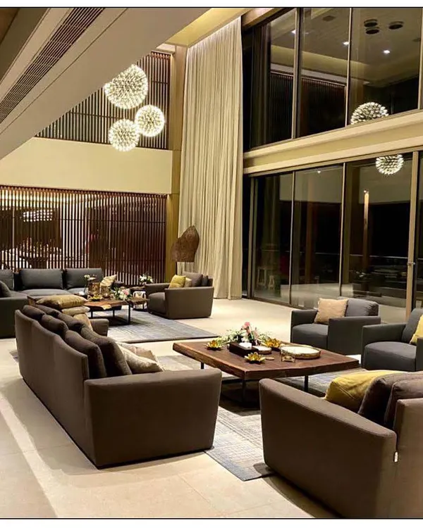 This living room in Aamby Valley showcases our approach to creating grand yet inviting spaces. The double-height ceiling and large windows connect the interior with the landscape, while multiple seating arrangements offer versatility for entertaining and family life.