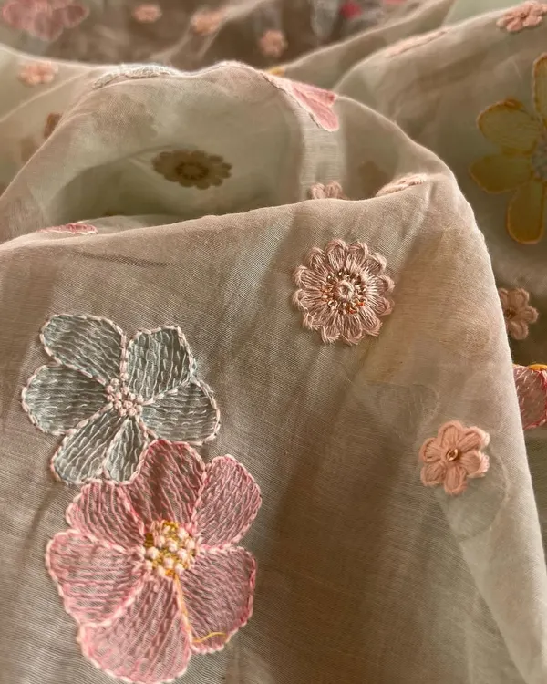 This close-up shows the exquisite detail of 3D floral embroidery on a soft Mul Chanderi base. The mix of pink and blue threads with pearl centers makes this fabric a piece of art, ready to be turned into a bespoke kurta.