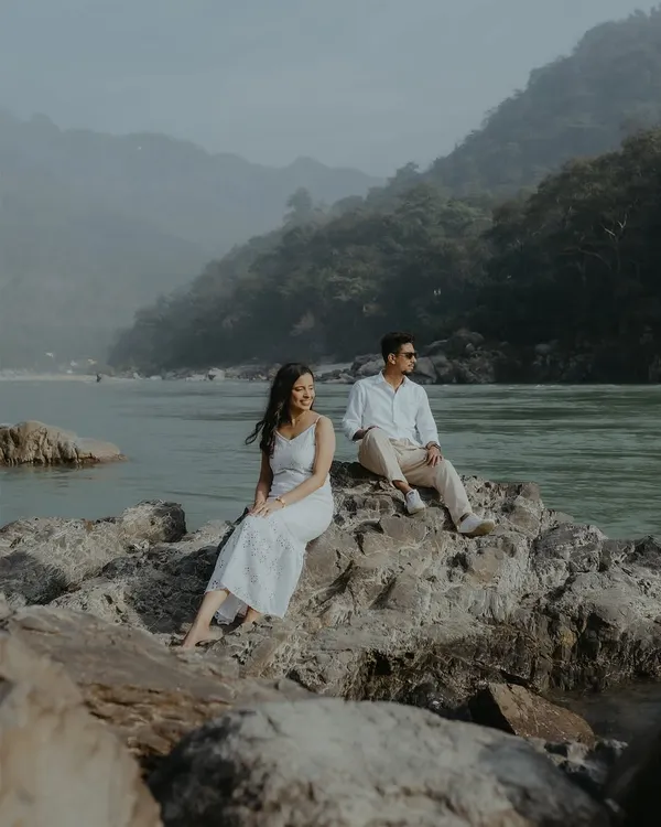 A serene couple portrait taken on the rocks by the Ganga river in Rishikesh. The majestic mountains and calm waters provide a breathtaking backdrop for this destination pre-wedding shoot.