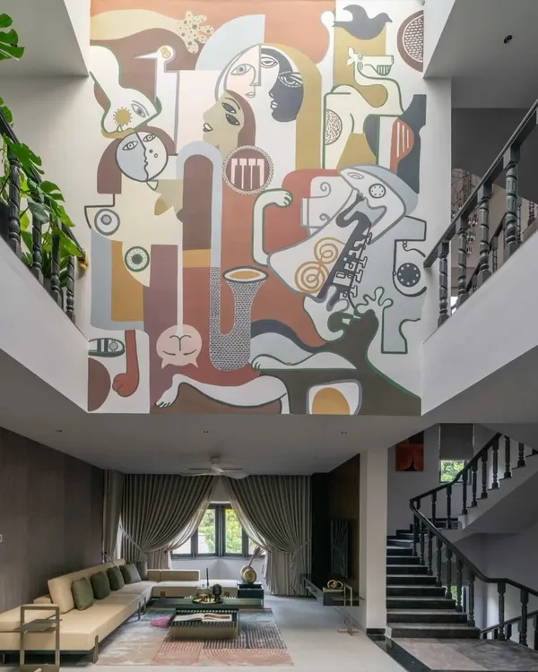This double-height mural in a living room is a perfect example of how art can become the central architectural feature of a home. The abstract composition of faces and forms draws the eye upward, creating a sense of grandeur and narrative depth.