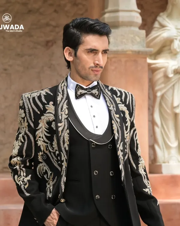 A detailed look at our black three-piece tuxedo with stunning gold and silver baroque embroidery. This is a signature piece from the Crown & Collar collection, designed for a groom's grand reception.