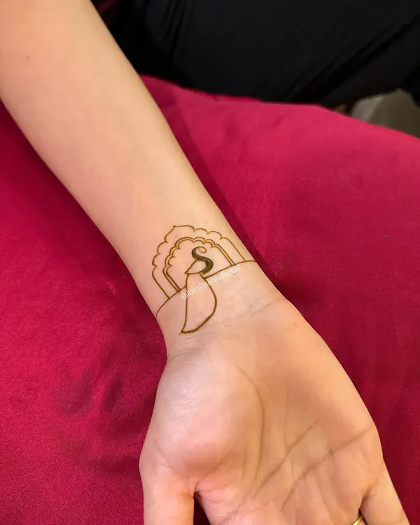 The start of a simple yet elegant wristband design. This piece begins with a single initial, 'S', set within a decorative frame.
