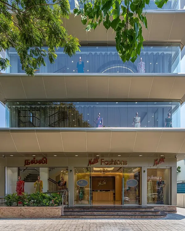 The completed facade of the Nalli flagship store in Anna Nagar, Chennai. The design features deep, ship-hulk-like overhangs that provide shade, create a dynamic visual, and nod to the Art Deco style of the original Nalli store.