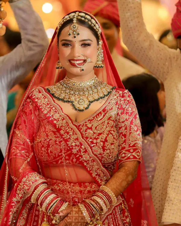The pure joy of a bride on her wedding day. This radiant smile says it all. We went for a classic red lehenga look with a bright lip and defined eyes, ensuring she looked and felt absolutely unforgettable.