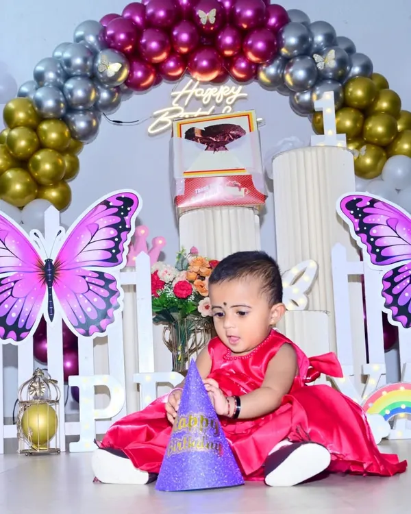 I focus on capturing the little moments, like this one from a first birthday party. The butterfly-themed decor and candid shot of the birthday girl with her party hat show how I combine photography with a great setup to create lasting memories.