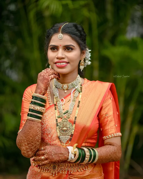 A professional portrait of a radiant Maharashtrian bride. I draped her orange wedding saree to highlight the intricate work on the pallu and ensure a perfect, photo-ready finish.