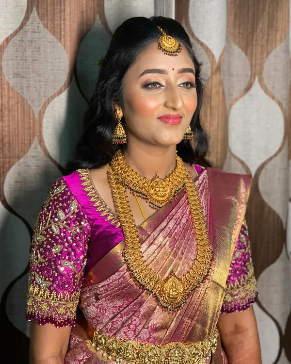 Bride Vidya's reception look is all about modern glamour. She wears a beautiful magenta Kanchipuram saree with a heavily embroidered blouse, which I paired with soft, open curls and glowing makeup.