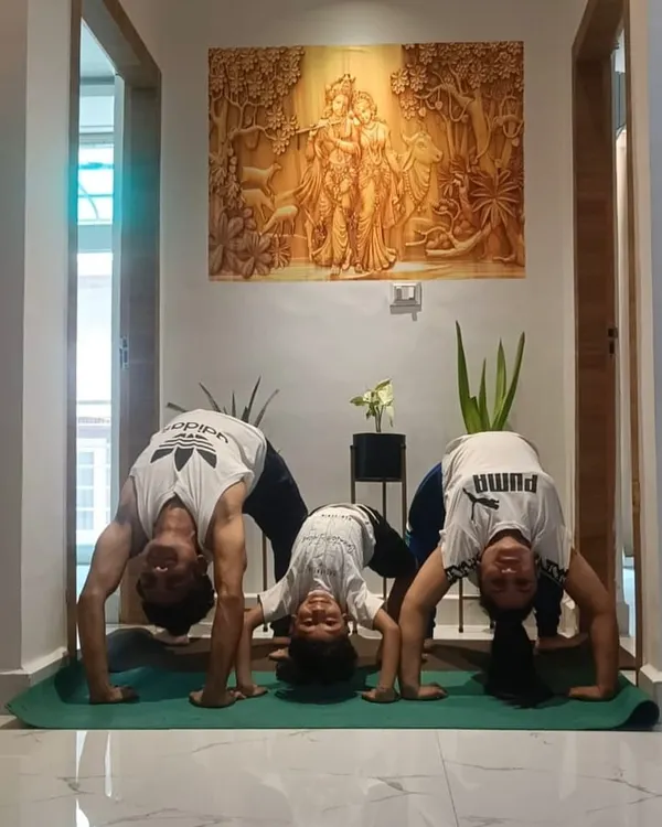 Getting the whole family involved in a yoga session at home. Here, we are all practicing the bridge pose, a great way to strengthen the back and improve flexibility for both adults and kids.