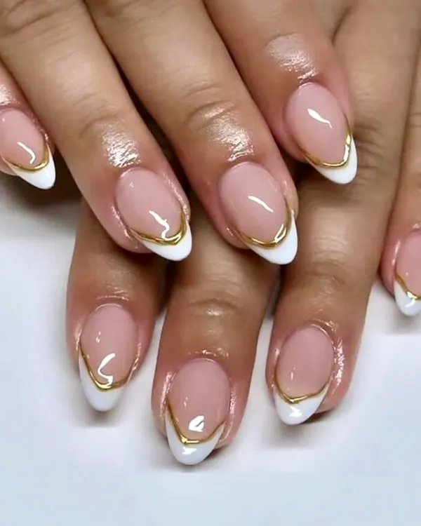 A perfect example of soft glam with a modern edge. This classic white French manicure on almond nails is elevated with a delicate, hand-painted gold line separating the tip from the nude base.