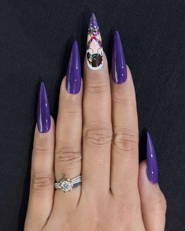 This is an example of my custom hand-painted character art on long stiletto nail extensions. I used a vibrant purple base and created a detailed, unique character on the accent nail to showcase my intricate design capabilities.