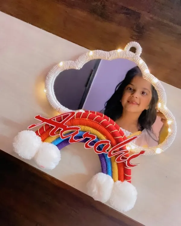 A personalized mirror is a wonderful gift. This cloud-shaped mirror for 'Aarohi' is framed with white macrame cord and includes fairy lights and a colorful rainbow name accent.
